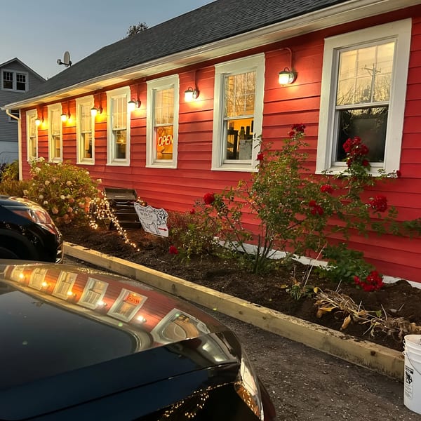 Exterior of Rustic Tables Restaurant & Bar, a red building with illuminated windows and an "OPEN" sign.