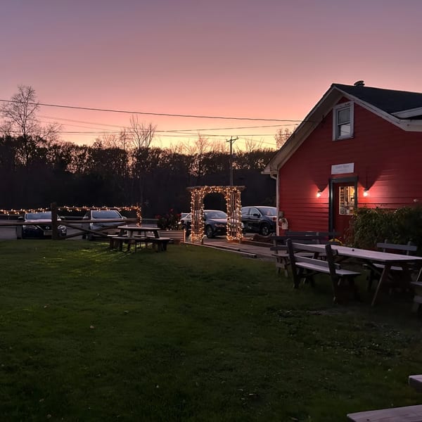 Rustic Tables Restaurant & Bar's red building and outdoor seating under a vibrant sunset sky.