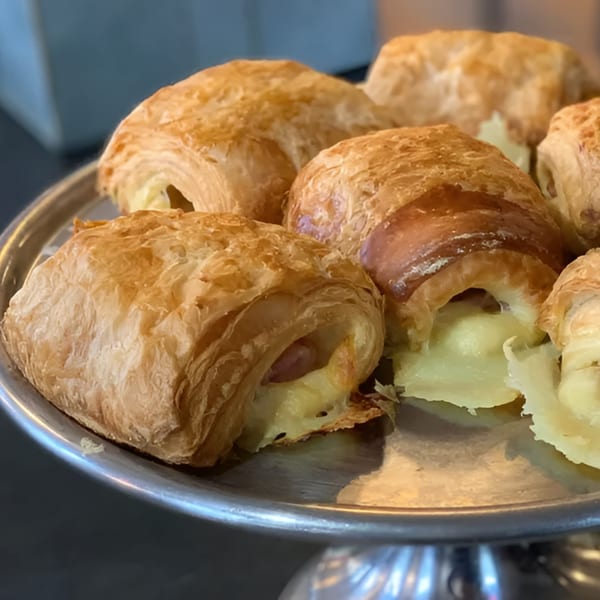 Golden-brown pastries with creamy filling on a silver tiered serving tray at Rustic Tables.